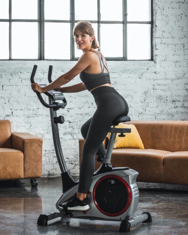 Billede af en kvinde som træner på AL 1 motionscyklen i en stue